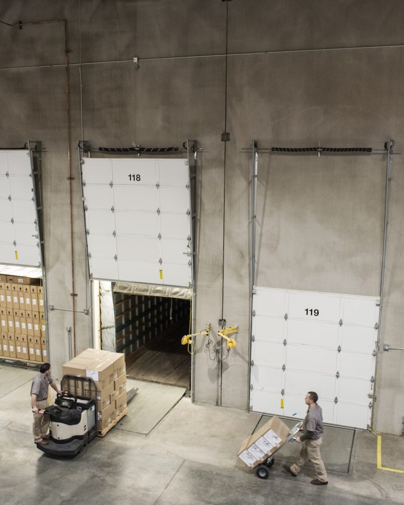 Uniformed warehouse workers loading boxed products into truck in a distribution warehosue.